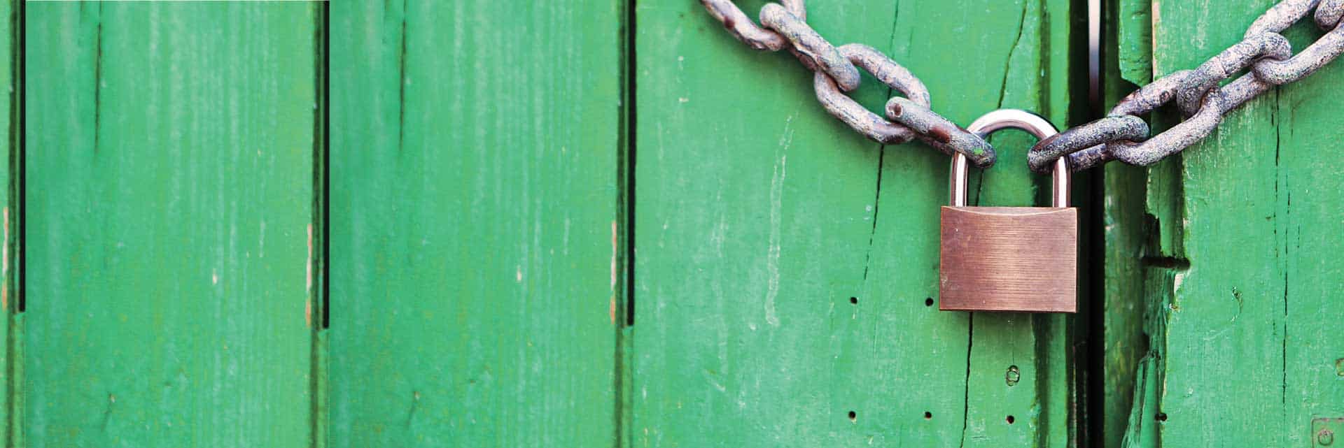 green wooden door locked with chain and padlock