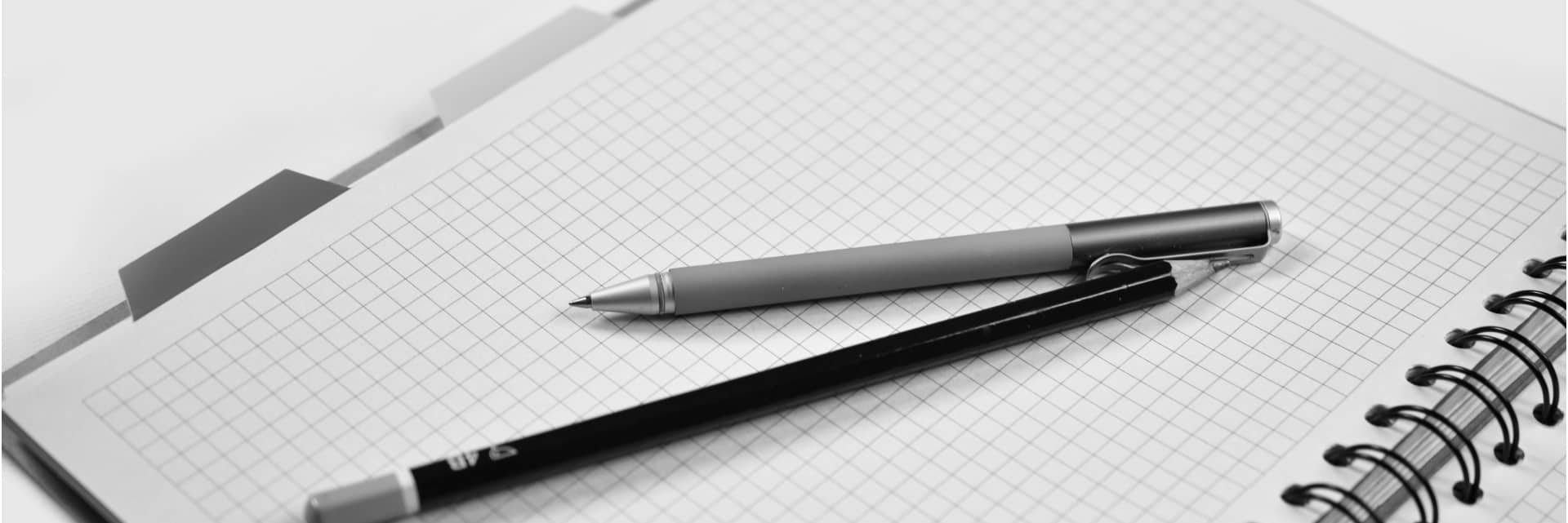 pen and pencil laying on opened graph paper notebook