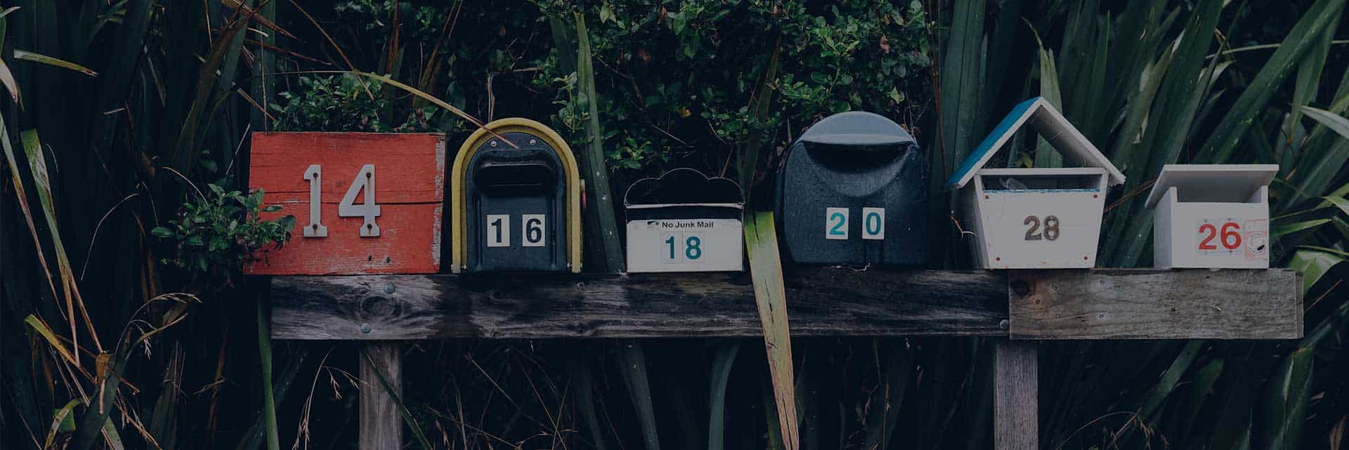 eclectic mailboxes on wooden holder